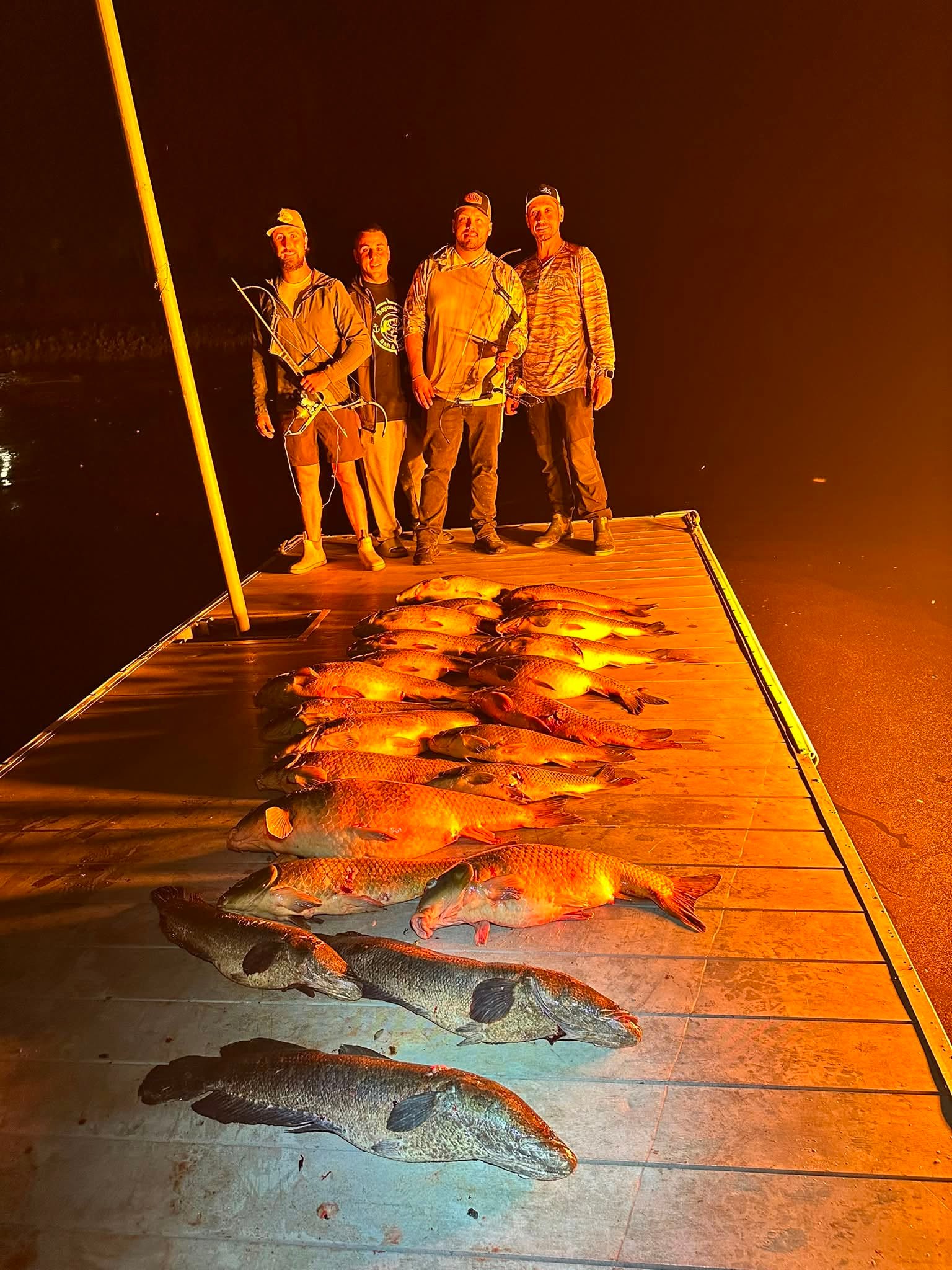 Group of bowfishing anglers with their catch on the dock at night