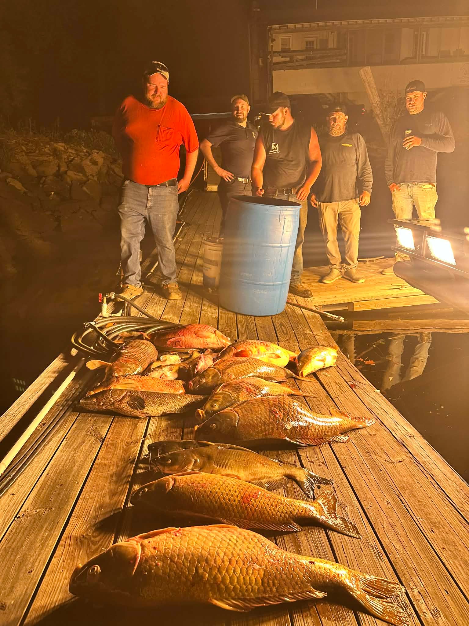 Two anglers with a boat full of carp and a striped bass catch