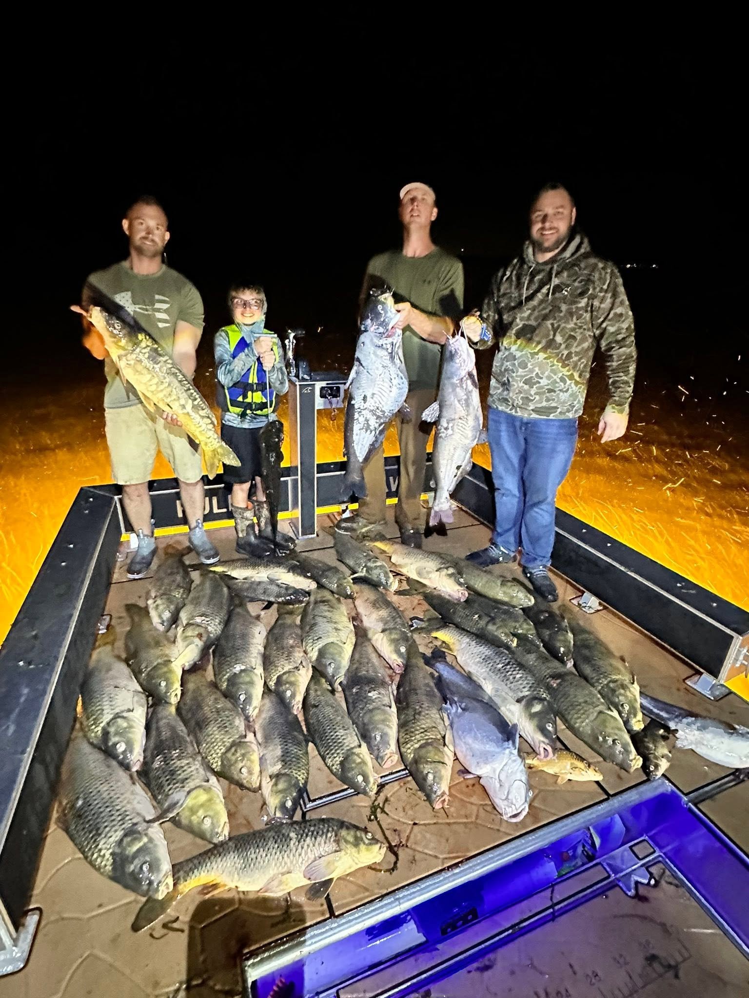 Angler holding a large carp caught bowfishing at night