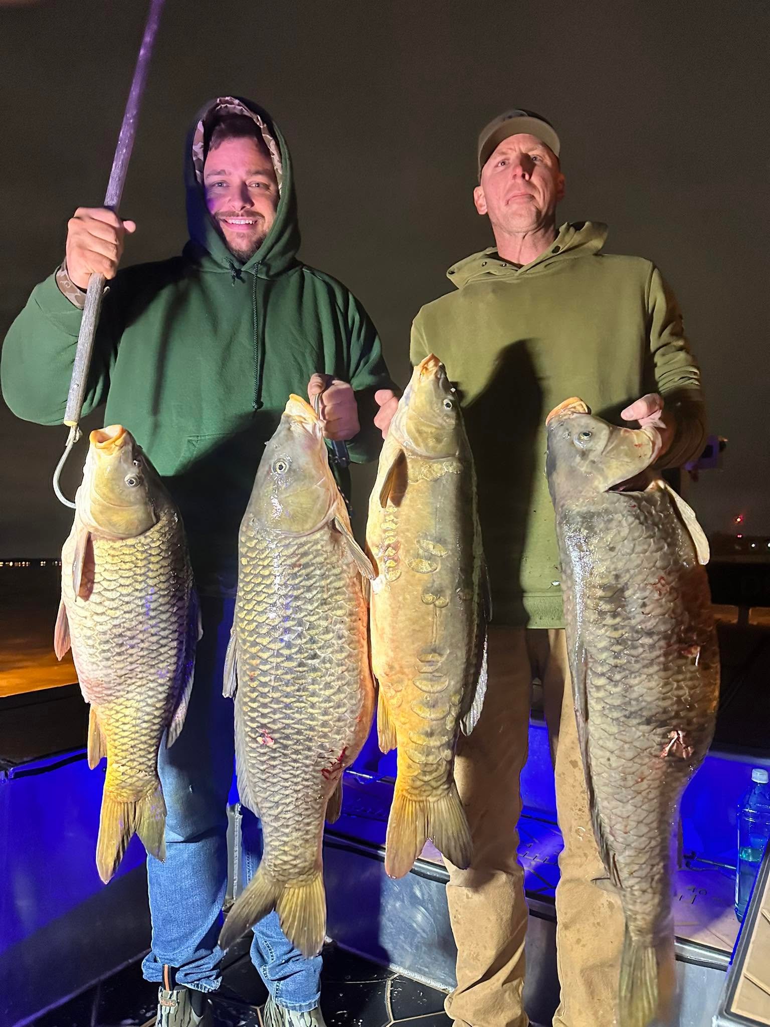 Young angler holding a large fish on a bowfishing arrow at night