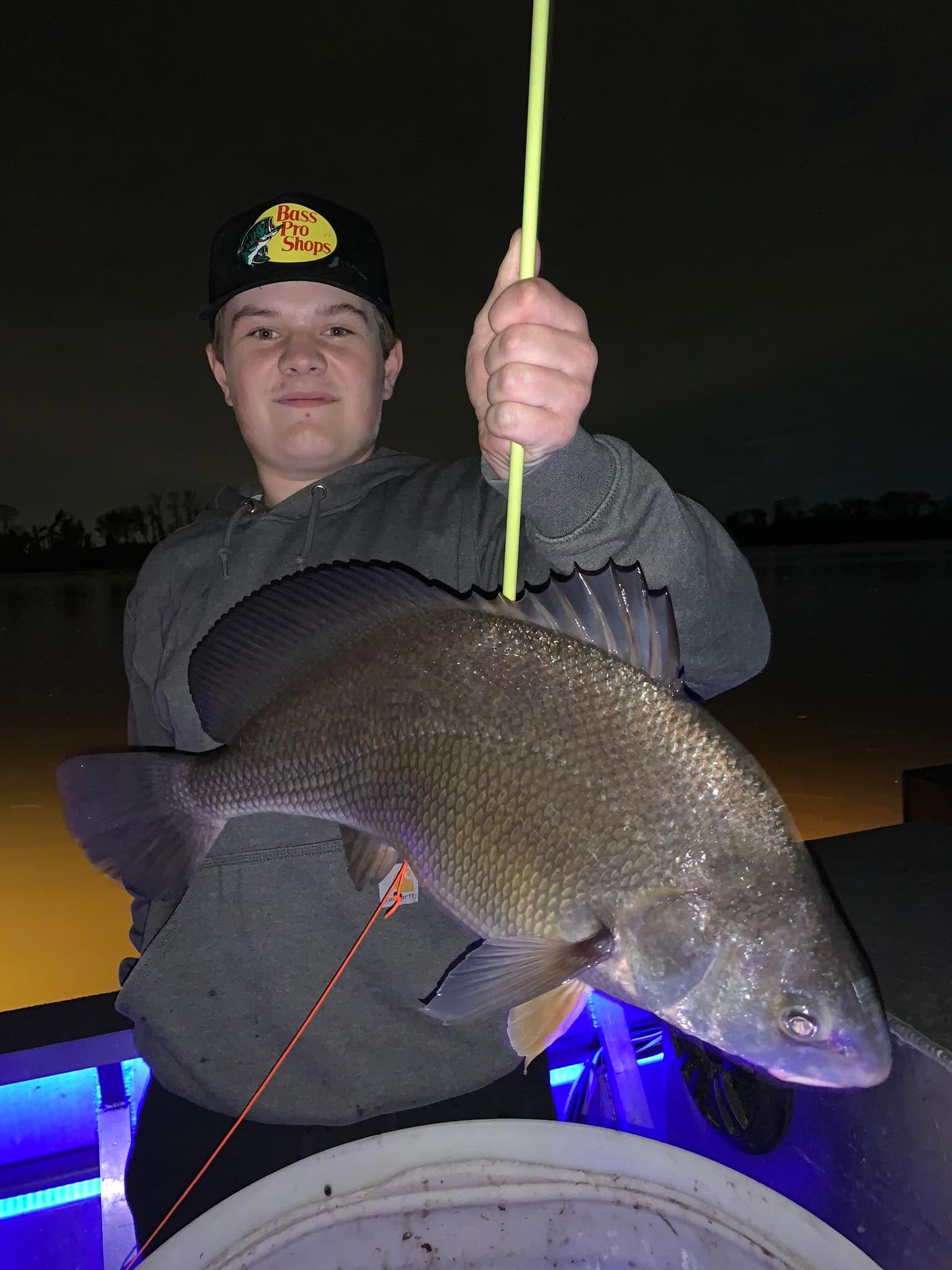 Family group with a large multi-species bowfishing catch on the dock at night