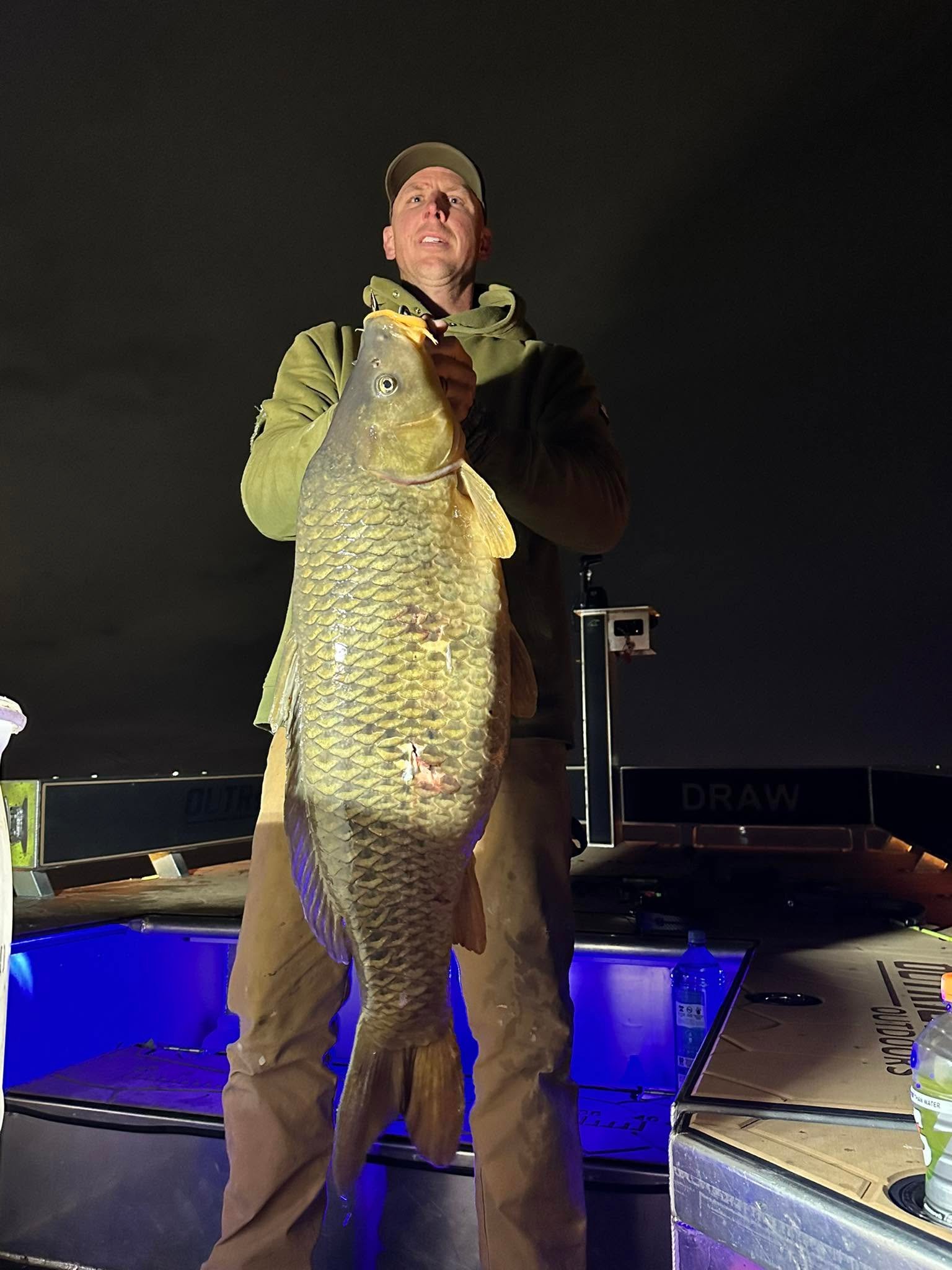 Angler holding a fish on the boat at night