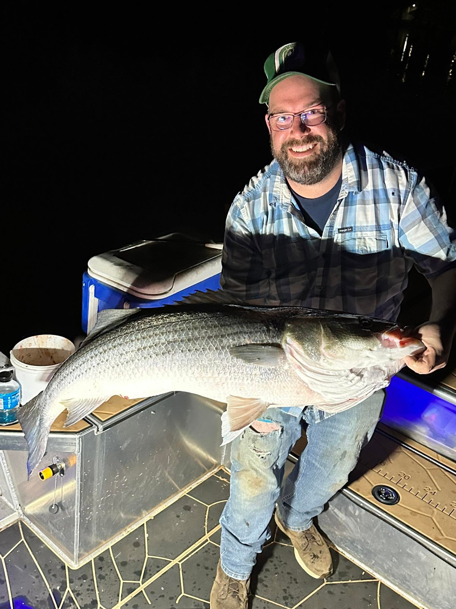 Angler holding a striped bass on the boat during the day