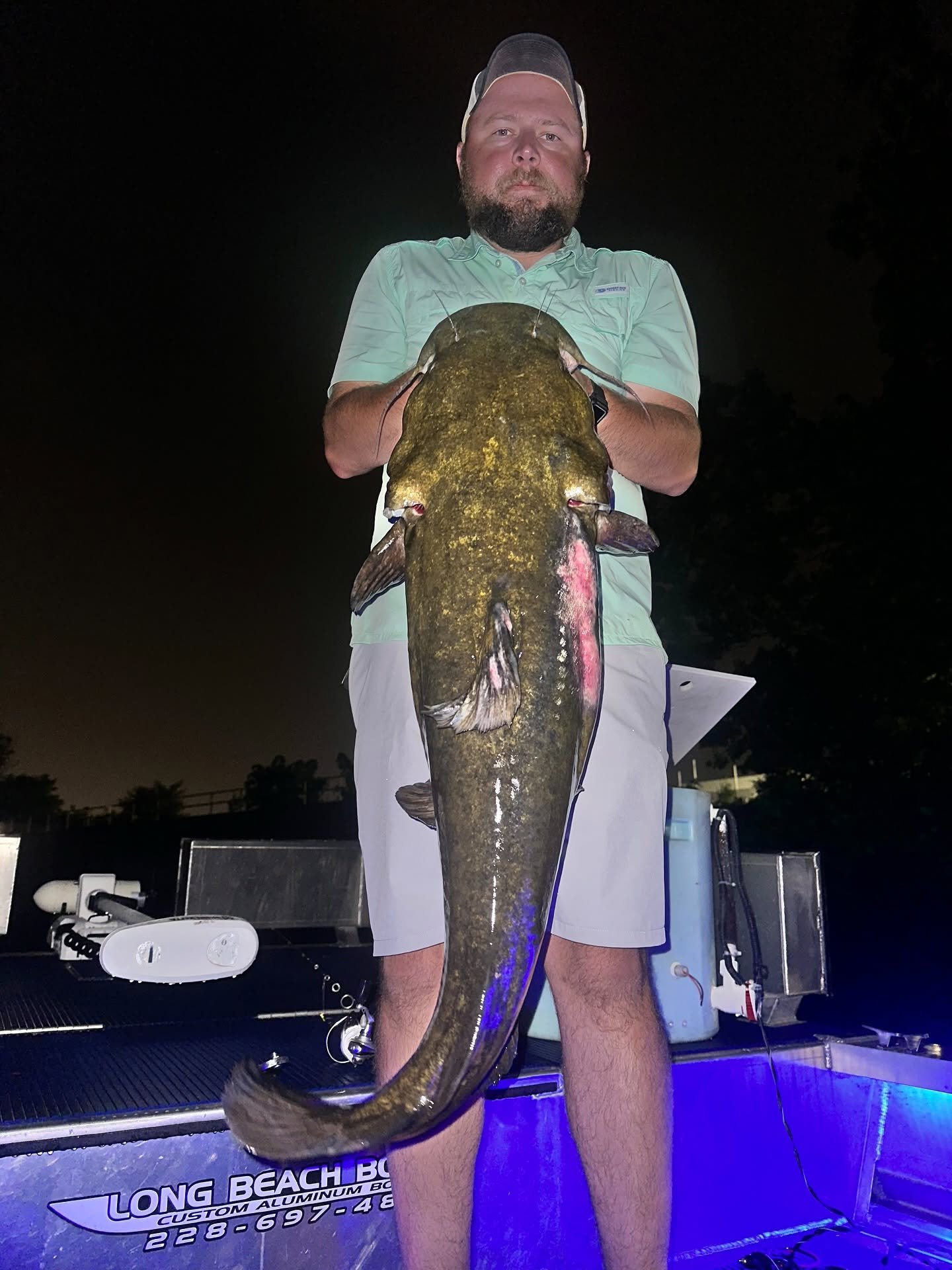 Angler holding a large flathead catfish at night